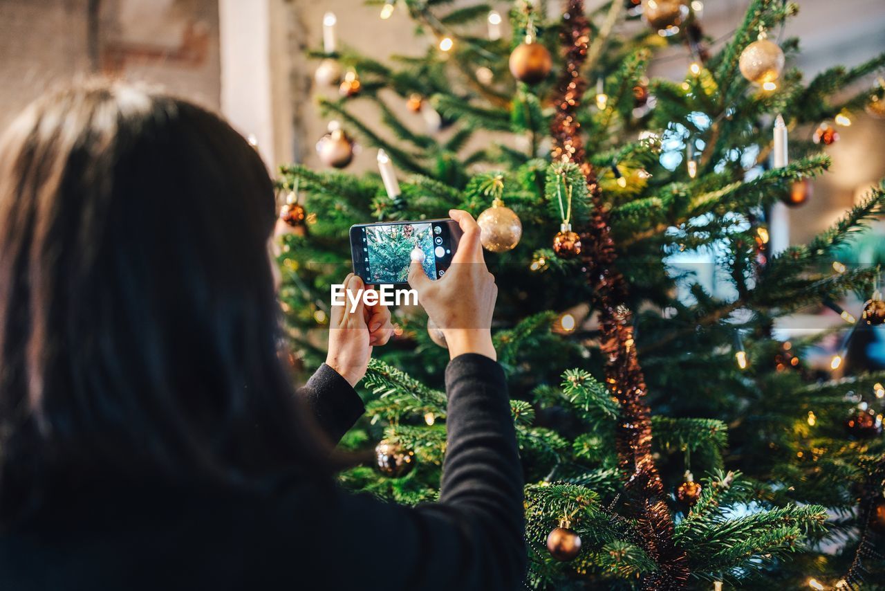 Rear view of woman photographing christmas tree