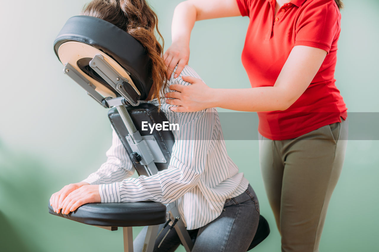 Female employee sitting on a portable massage chair in business office