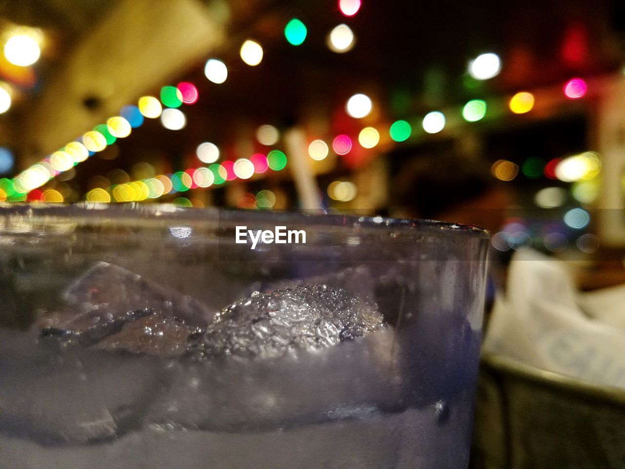 Close-up of drink glass against illuminated lights at night