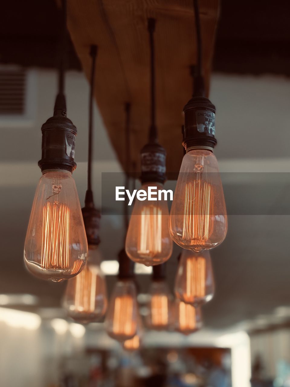 Close-up of illuminated light bulb hanging at ceiling