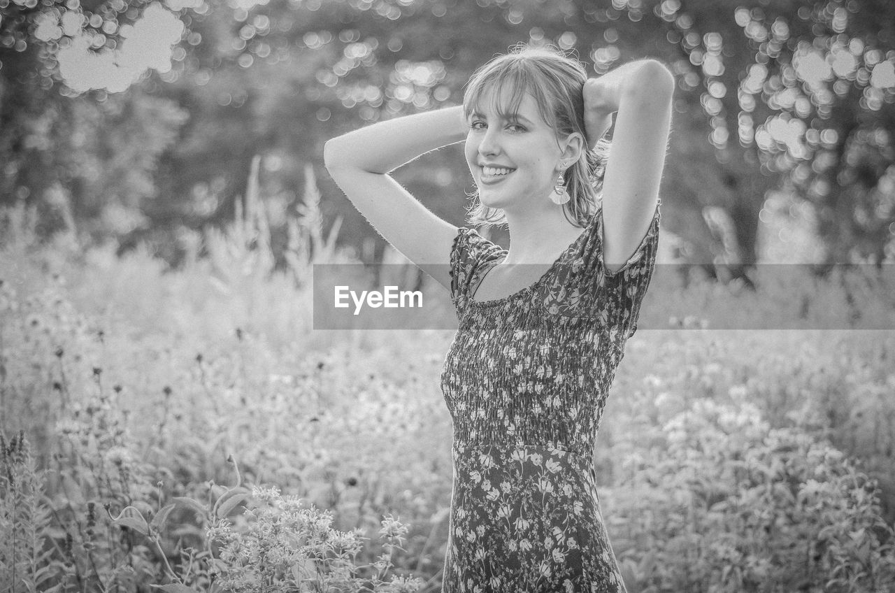 Portrait of smiling young woman standing at field