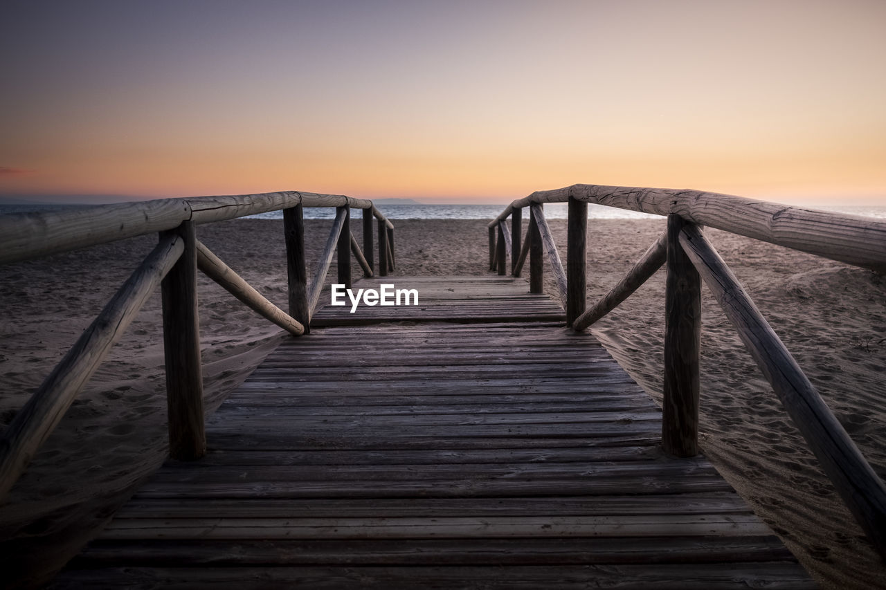 Pier over sea against sky during sunset