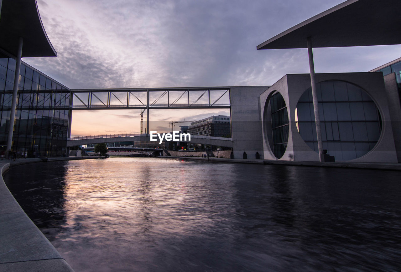 Bridge over river in city against sky