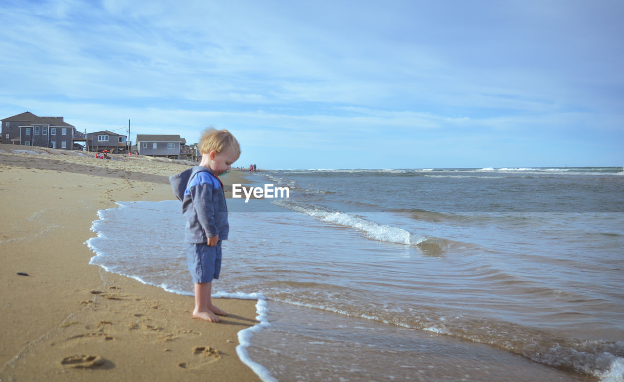 Full length of boy on beach against sky