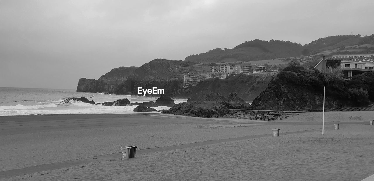 SCENIC VIEW OF BEACH BY MOUNTAINS AGAINST SKY