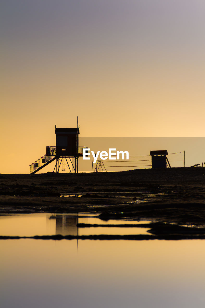 SILHOUETTE BUILT STRUCTURE BY SEA AGAINST CLEAR SKY