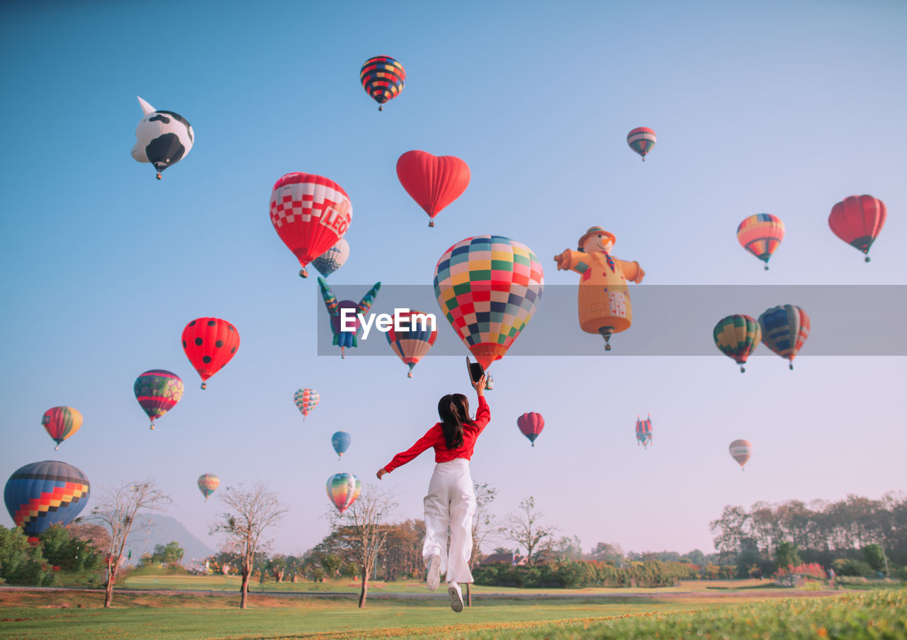 MULTI COLORED HOT AIR BALLOON FLYING OVER FIELD