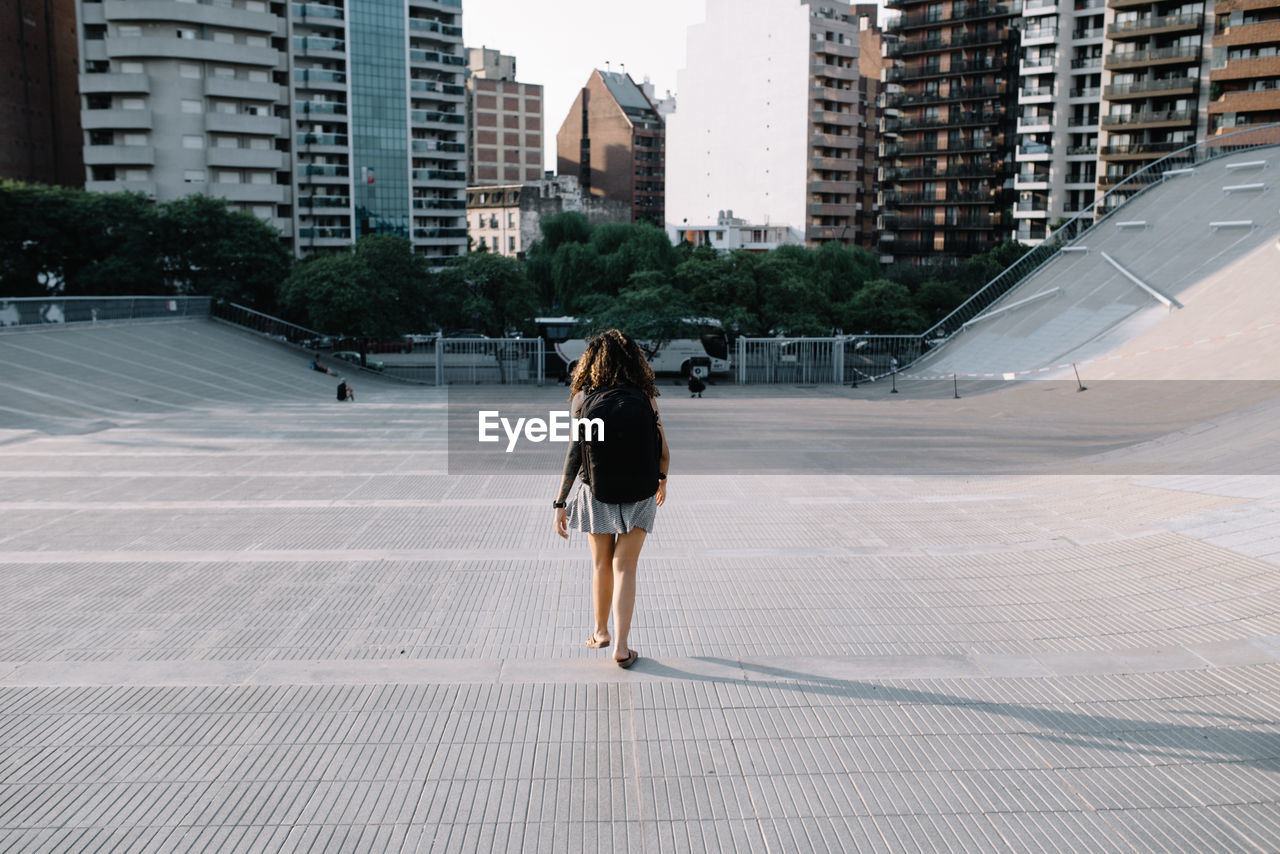 Rear view of woman walking on modern buildings in city