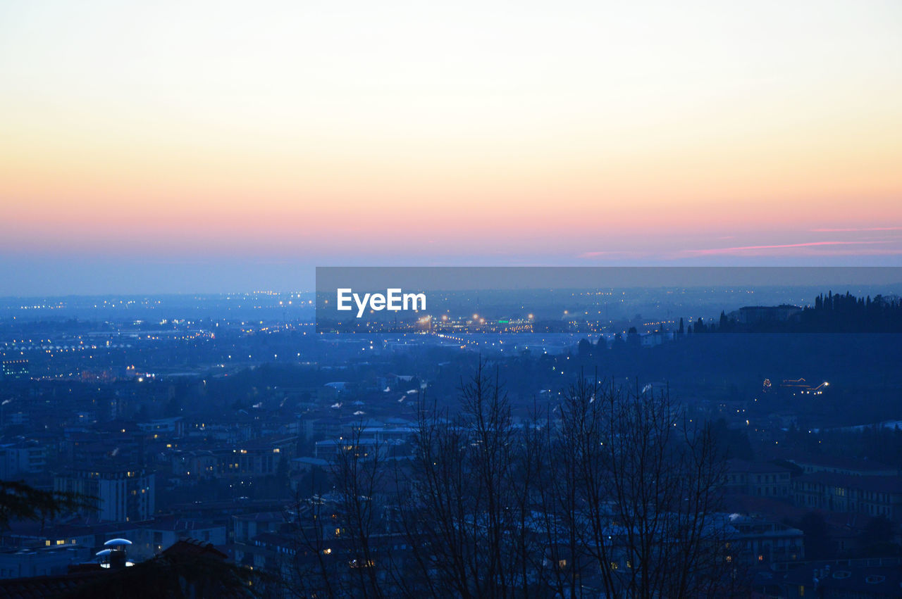 AERIAL VIEW OF CITYSCAPE AGAINST SKY AT SUNSET