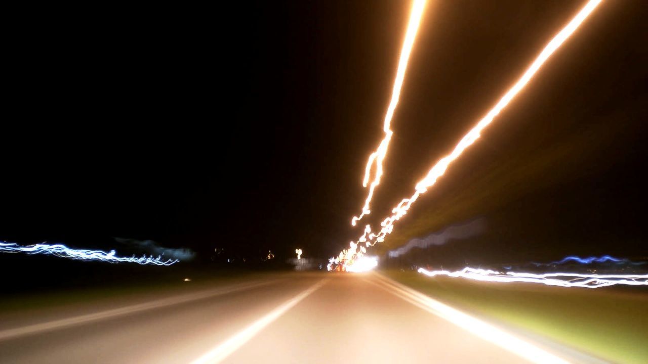 ROAD PASSING THROUGH ILLUMINATED TUNNEL AT NIGHT
