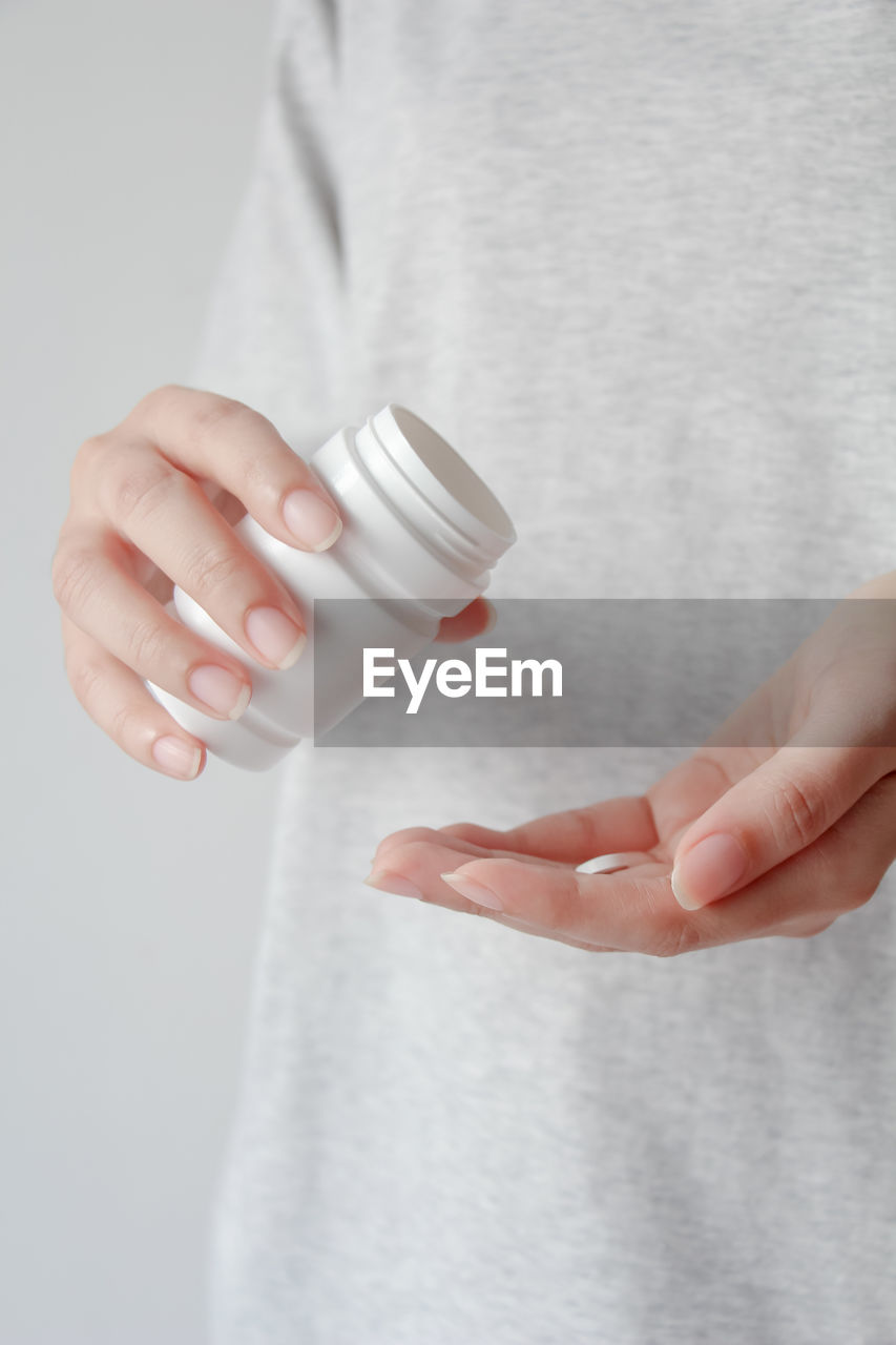 Close up of female hands pouring medicine tablets from bottle into her hand