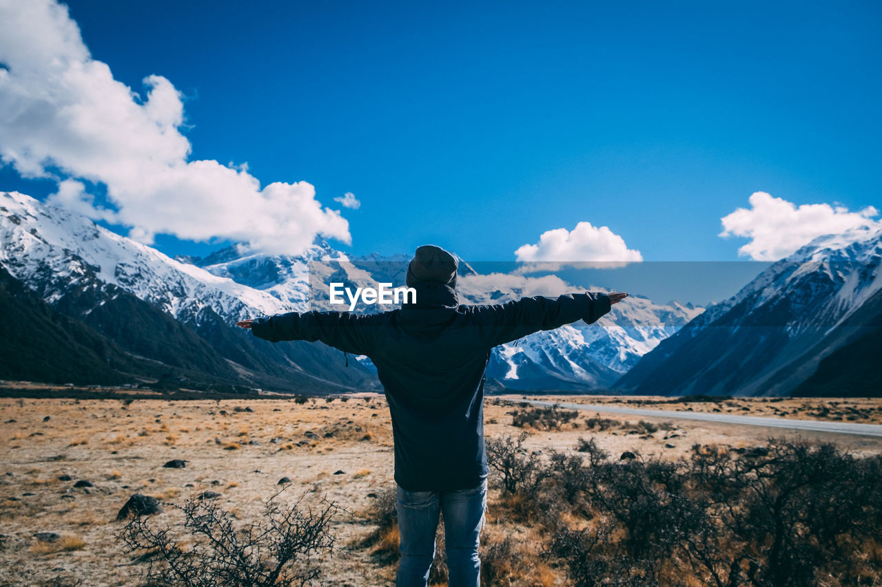 Man standing on field against snowcapped mountains