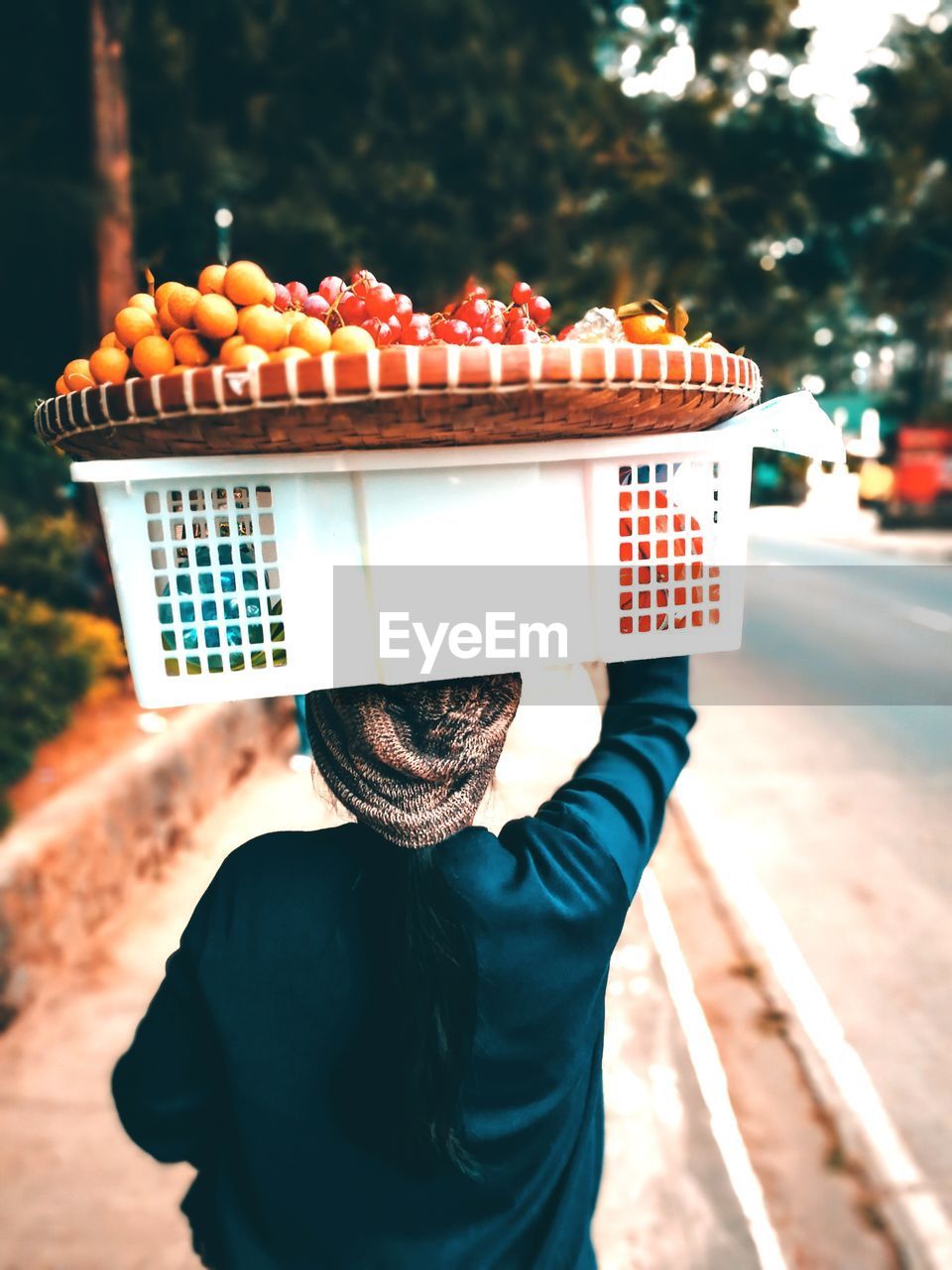 Rear view of woman selling fruits on sidewalk in city