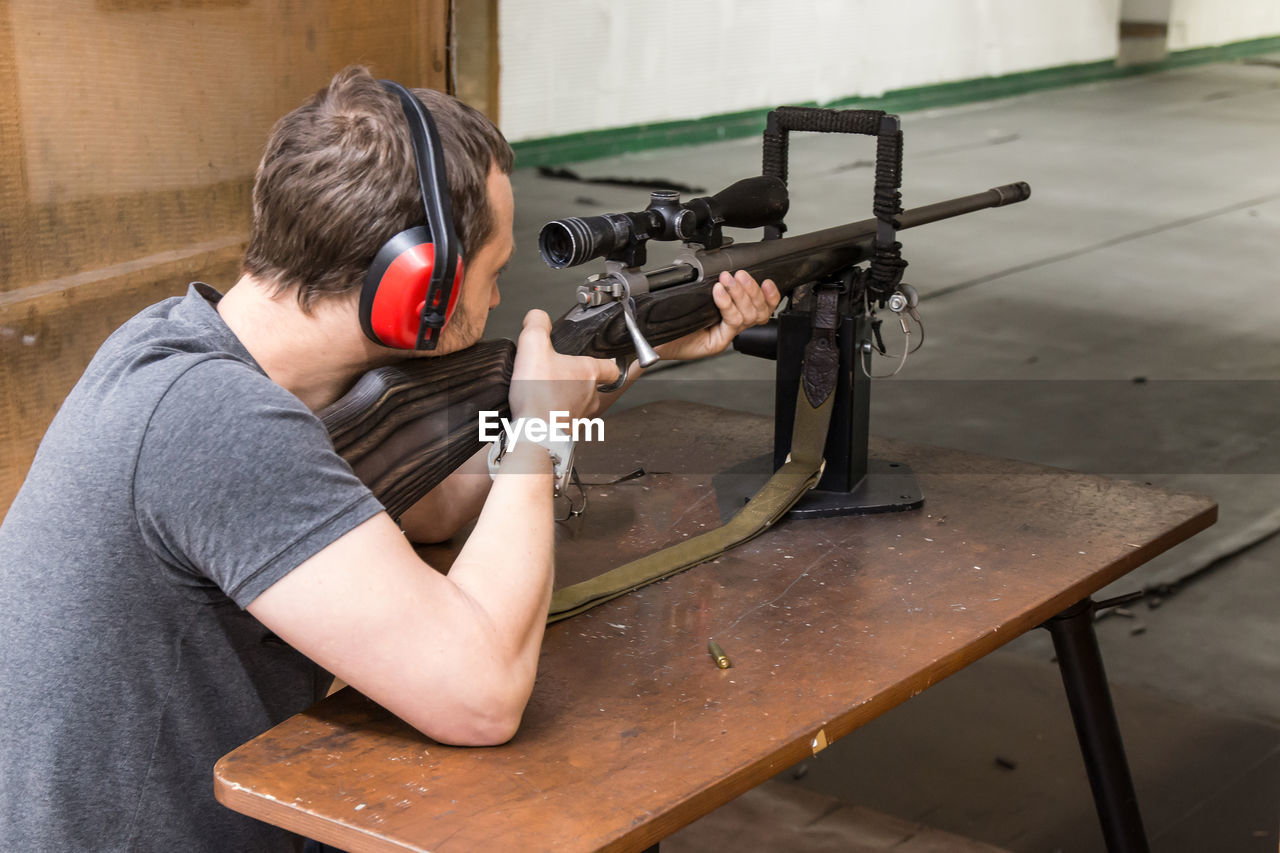 Midsection of man using rifle