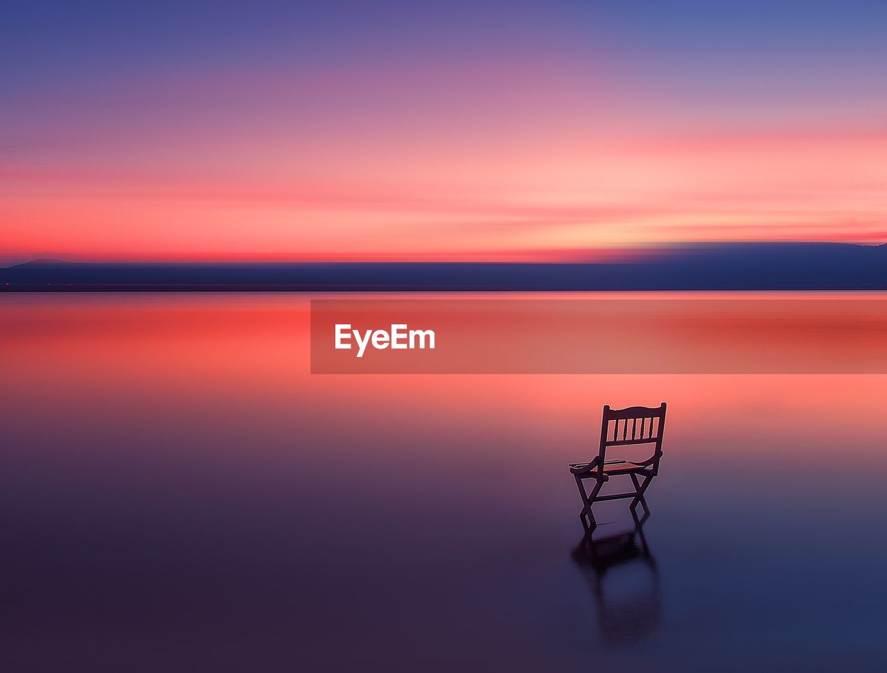 Beautiful scenery lake with long exposure sunset and wooden chair