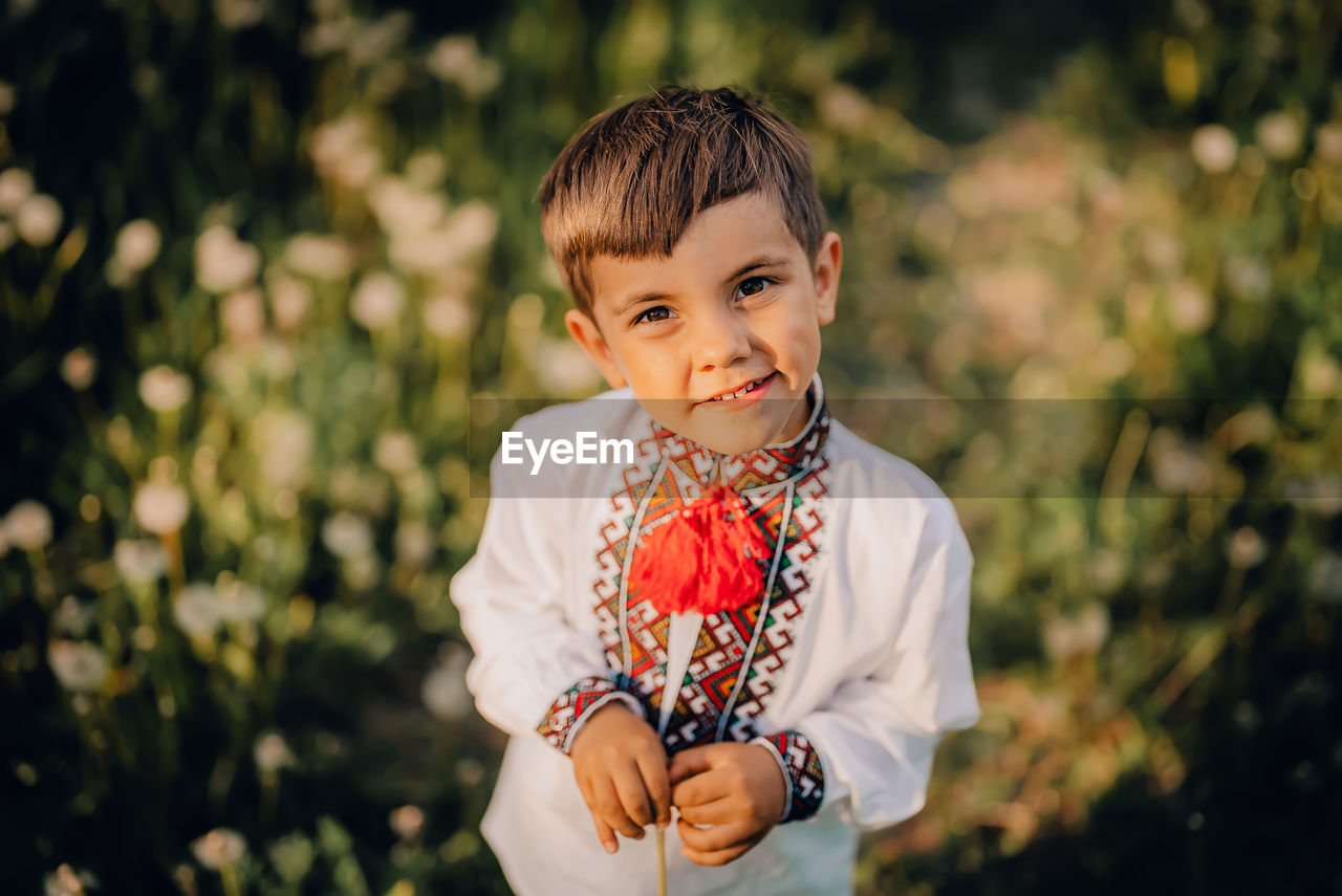 Portrait of boy standing against plants