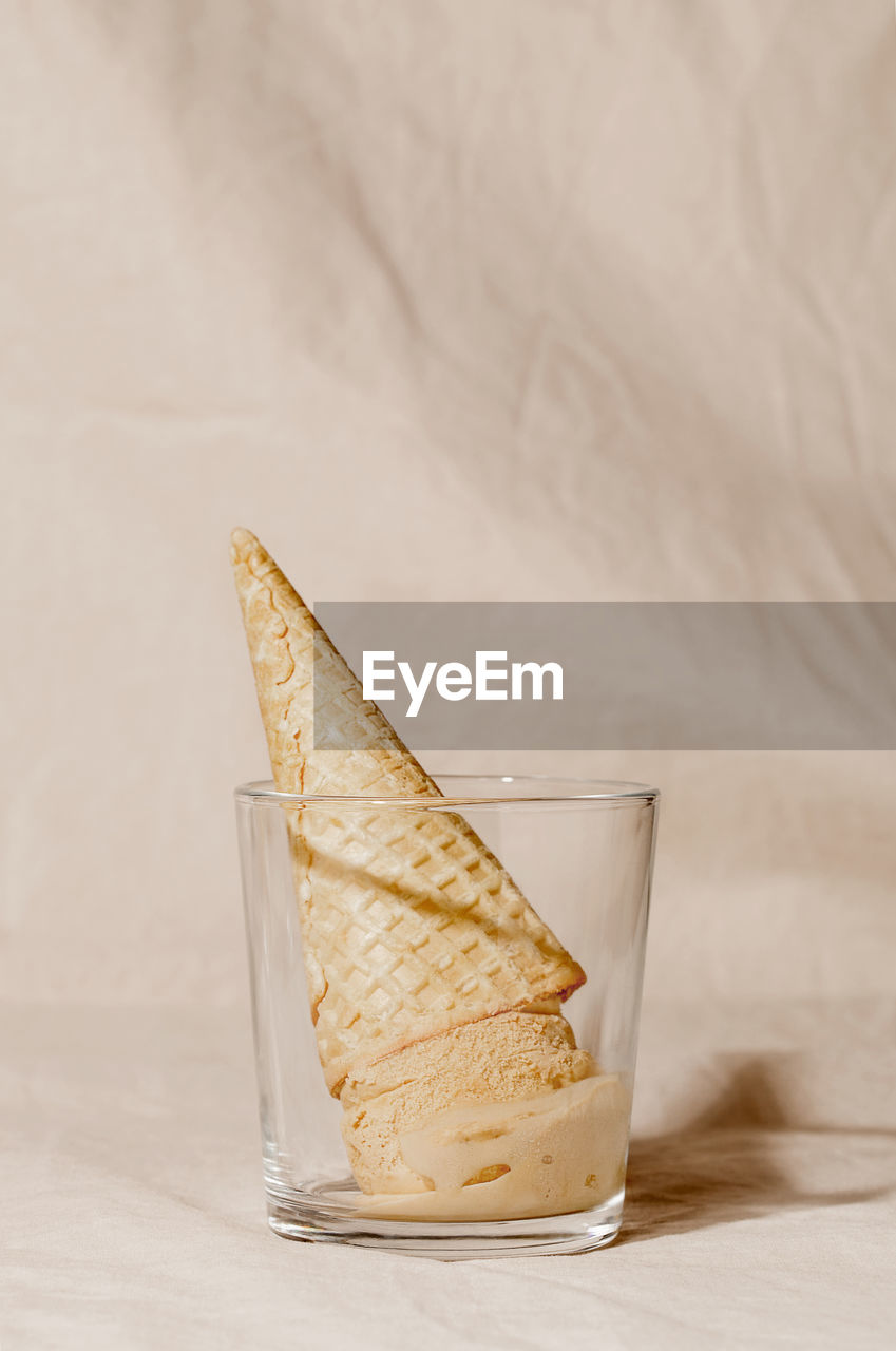 Corn ice cream waffle cone in glass on beige pastel background. summer creative concept