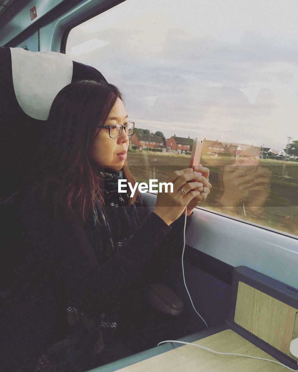 Woman photographing using smart phone in train