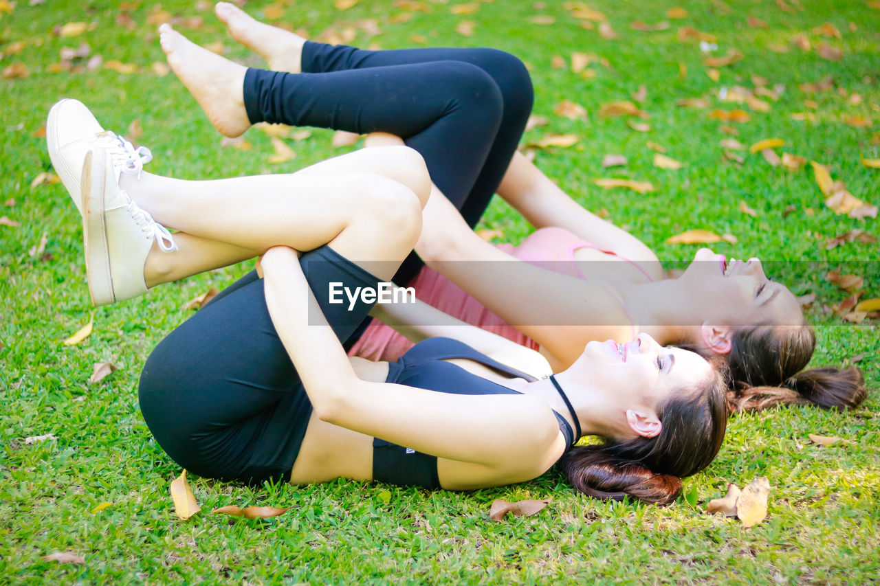 Side view of young female friends exercising on field