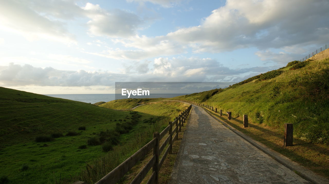 Road amidst field against sky