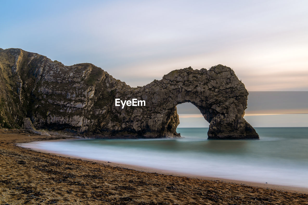 Rock formation on beach against sky