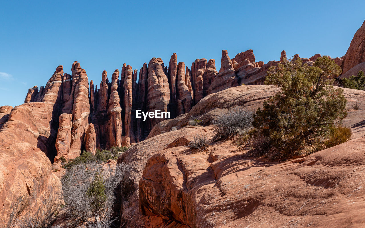 Full frame view of vertical fin-like sandstone formations against a clear blue sky