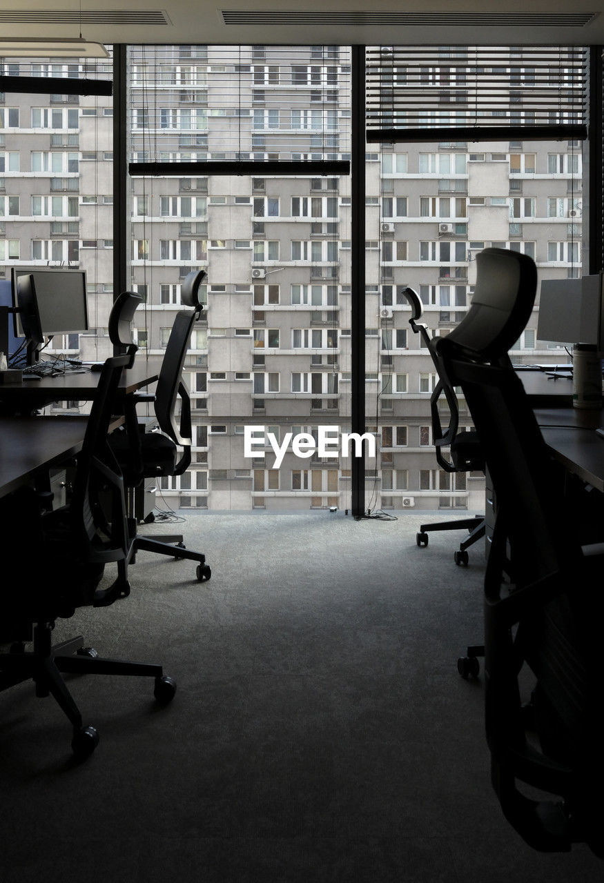 building, indoors, furniture, office, room, office chair, black, chair, architecture, bookshelf, seat, adult, sitting, office building, desk, shelf, table, business, library