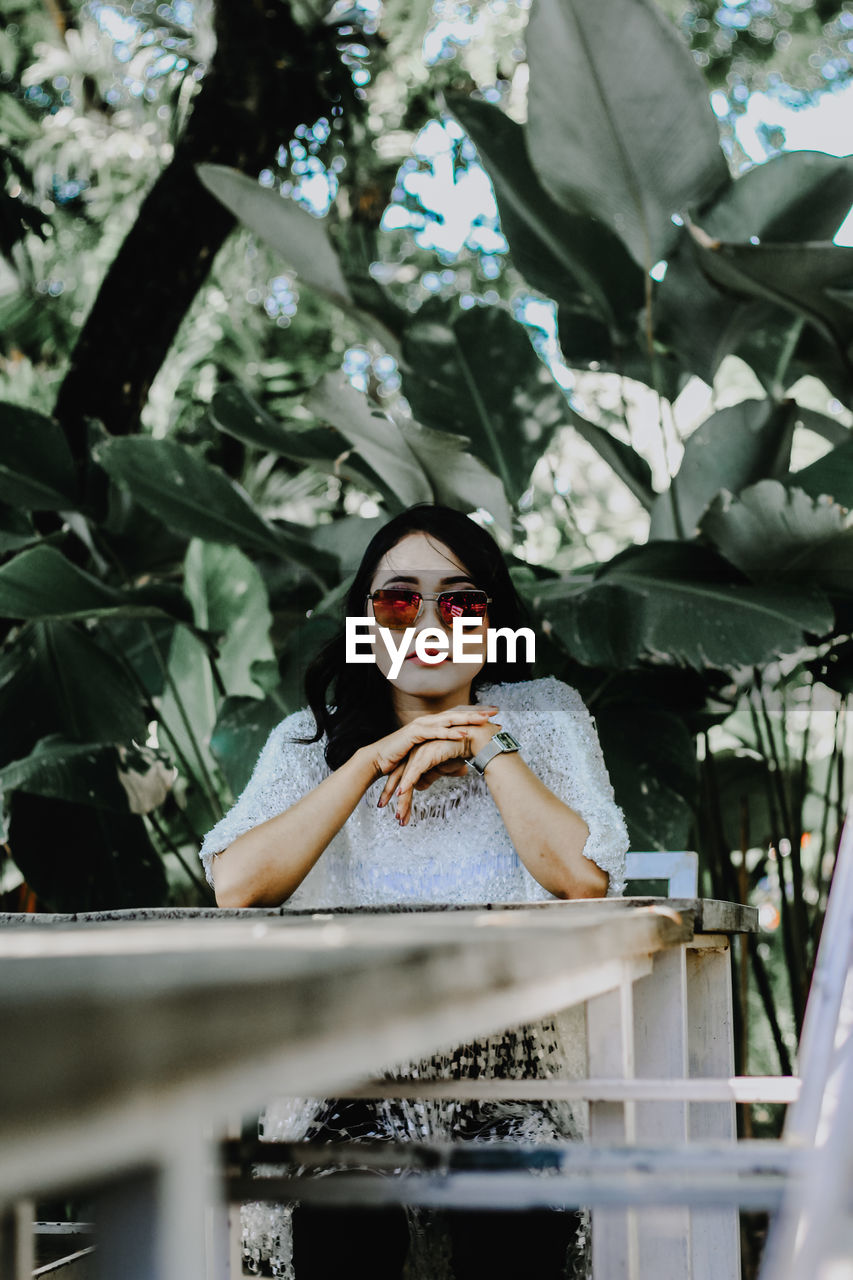 Portrait of young woman standing against plants