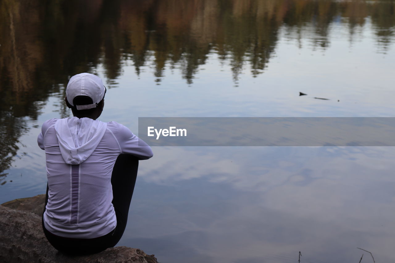 Rear view of woman sitting by lake