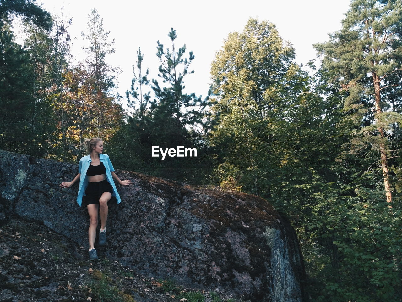 Young woman standing on field by rock