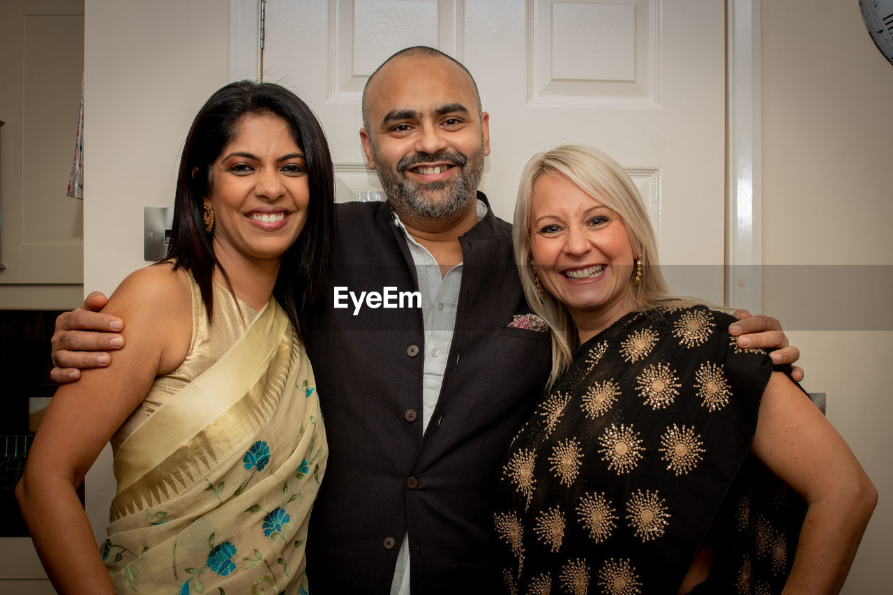 Portrait of smiling friends standing against door