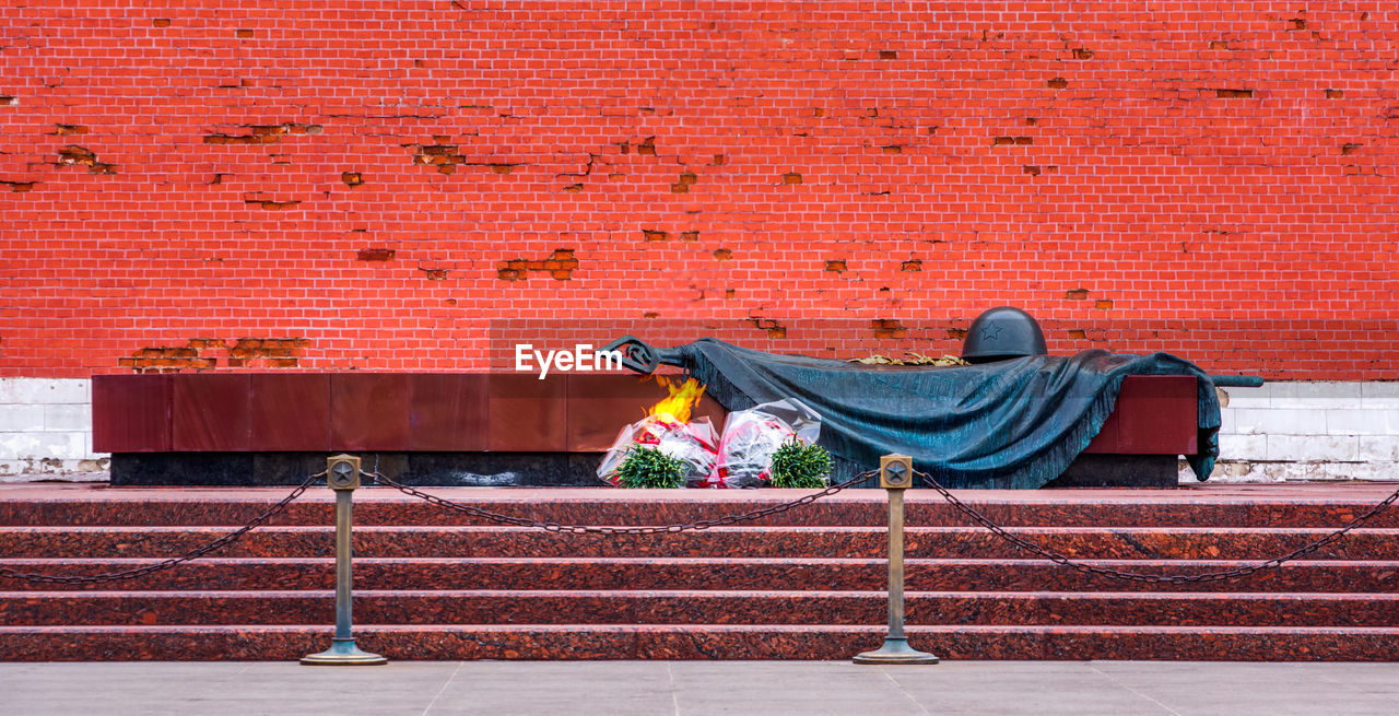 MAN SLEEPING ON RED BRICK WALL