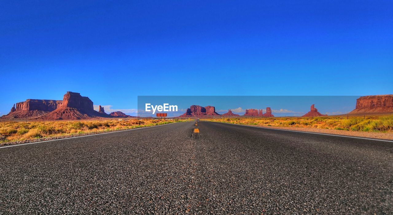 Surface level of road against clear blue sky an rocky formations