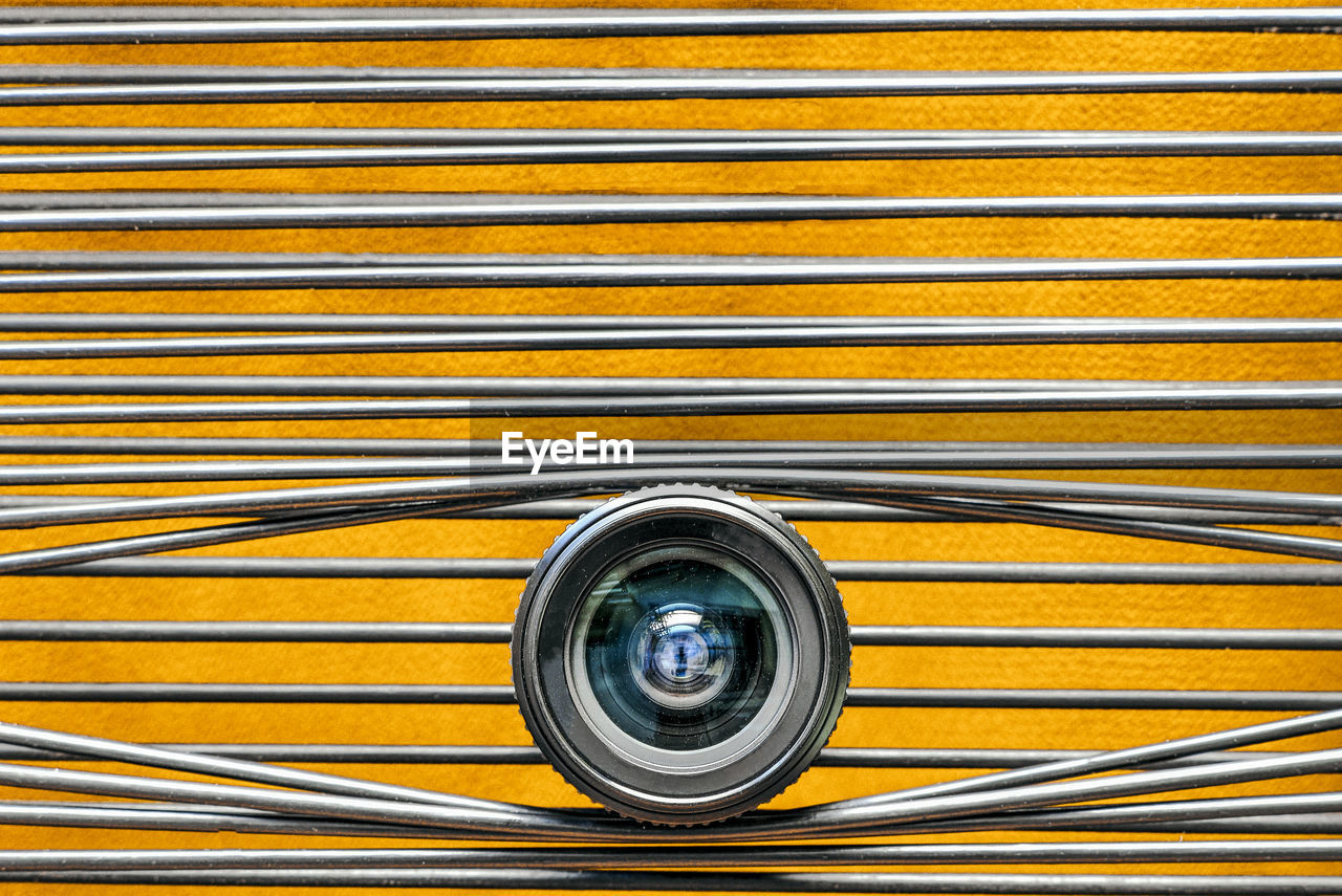 Close-up of camera lens against yellow background