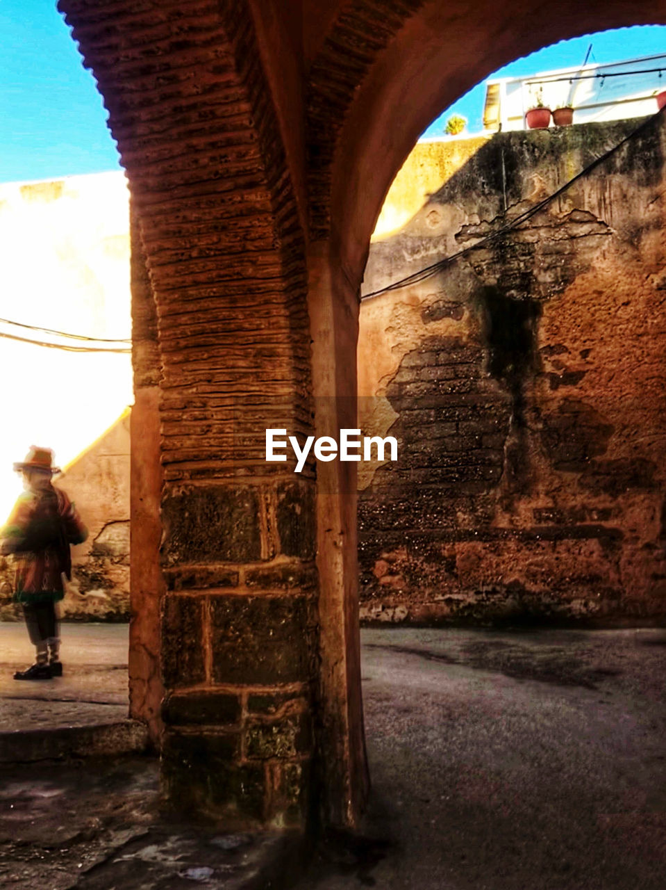 MAN SEEN THROUGH ARCH BRIDGE AGAINST SKY