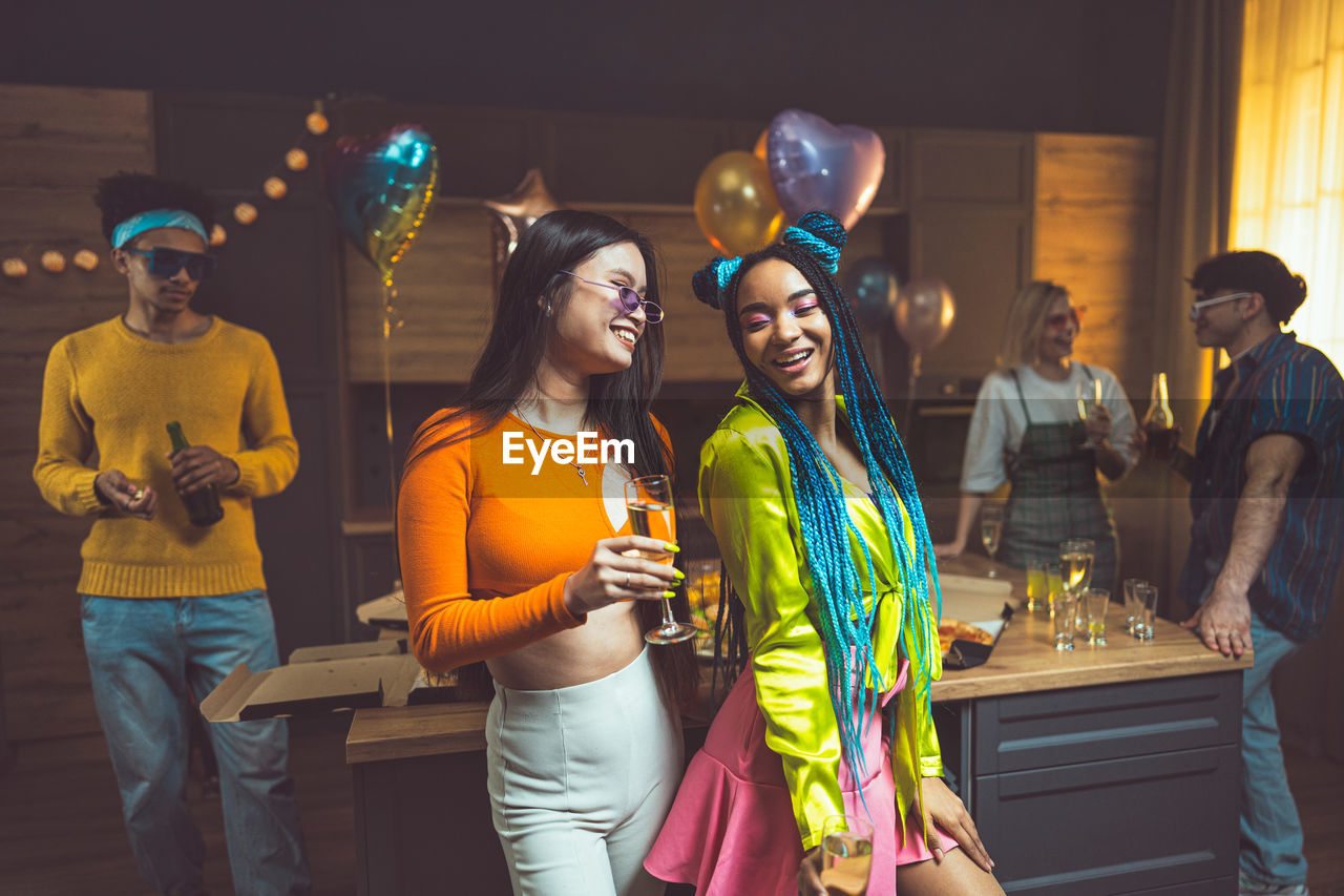 portrait of smiling friends standing in city at night