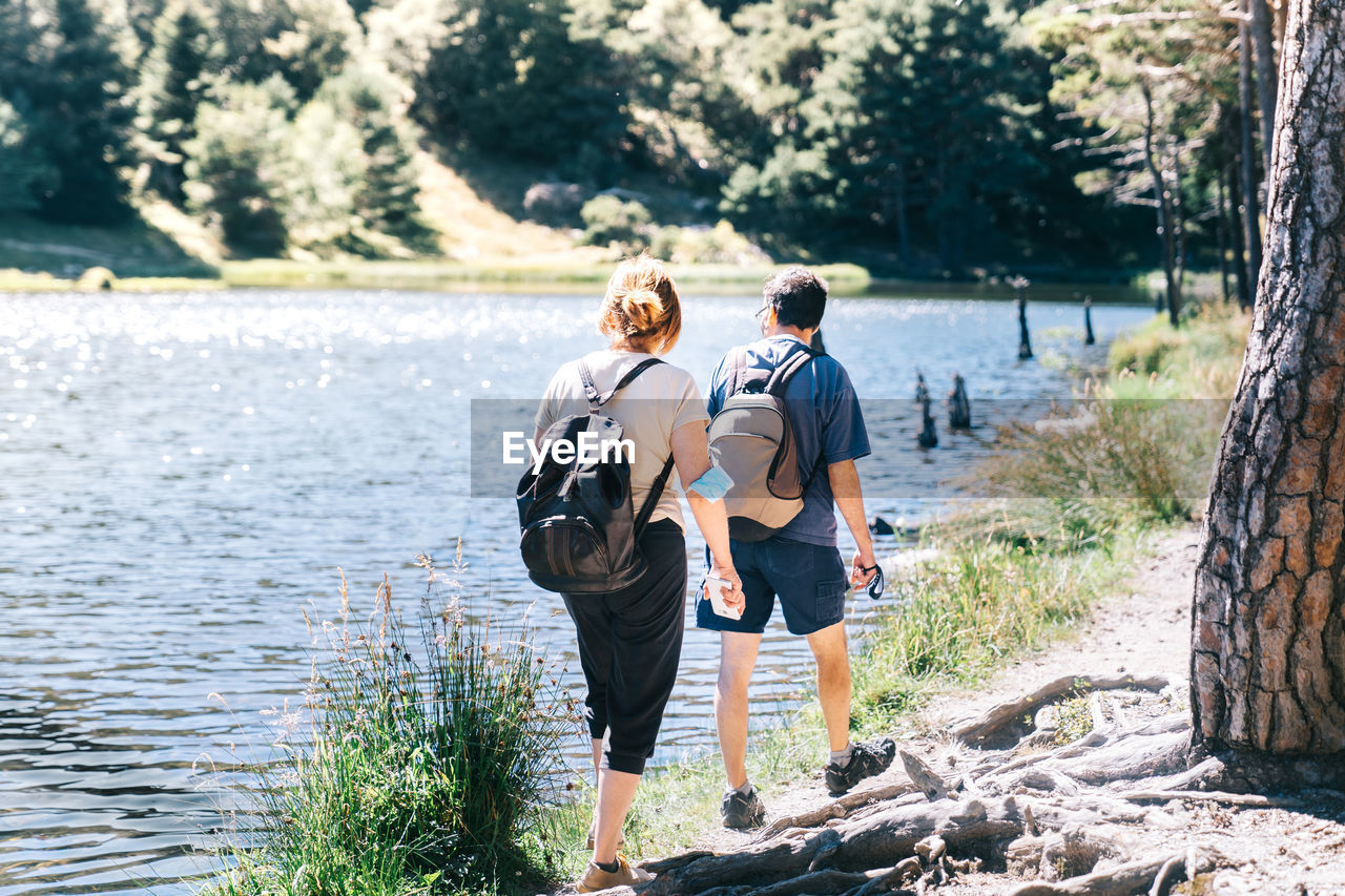 Mature couple walking by a lake with a medical face mask in times of the coronavirus pandemic