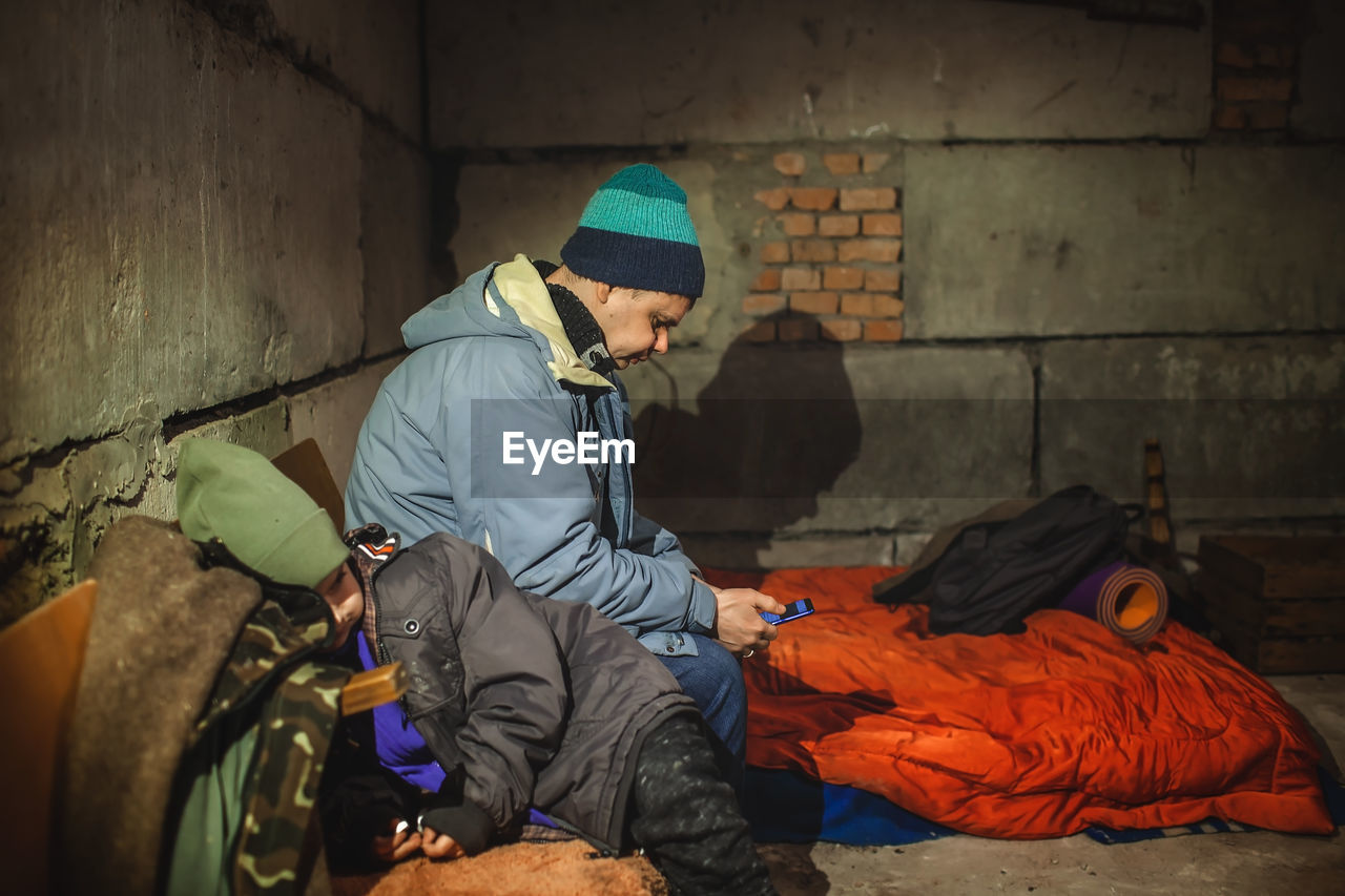 Side view of man using mobile phone at shelter