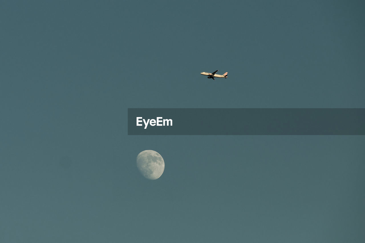 sky, moon, flying, no people, nature, low angle view, clear sky, space, night, copy space, beauty in nature, air vehicle, scenics - nature, astronomy, transportation, tranquility, outdoors, airplane, mode of transportation, blue, tranquil scene, astronomical object, full moon, mid-air, planetary moon