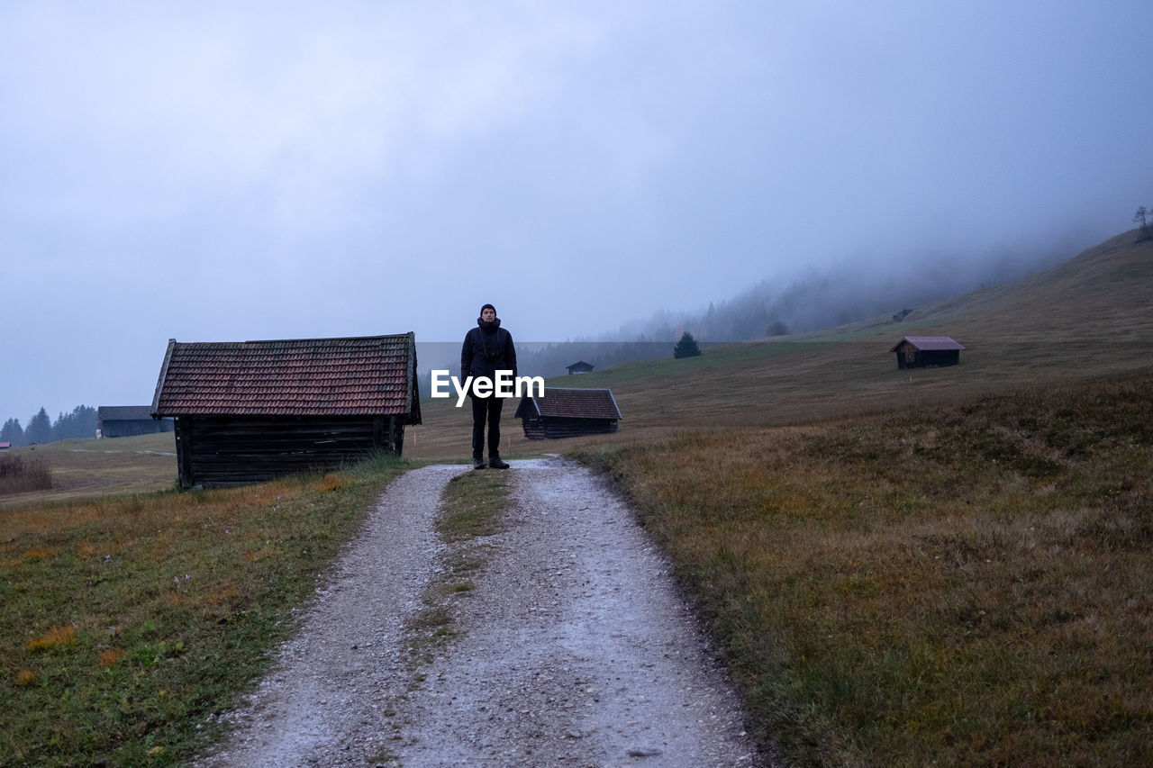 Rear view of man walking on field against sky