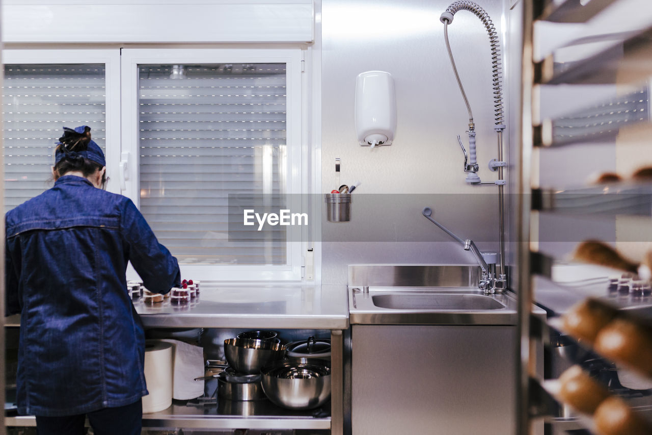 Rear view of female chef making food in commercial kitchen