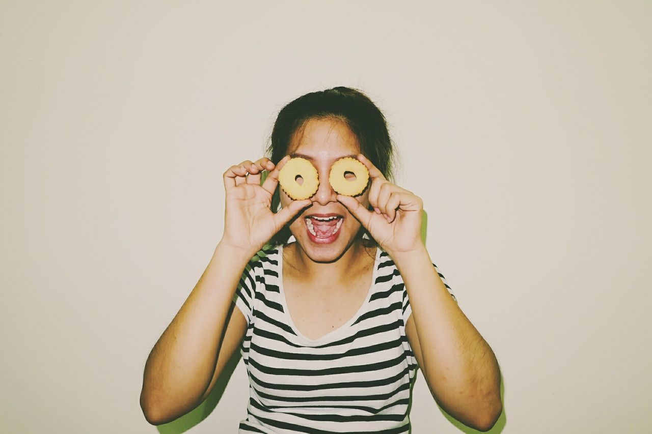 Portrait of happy girl holding cookies over eyes