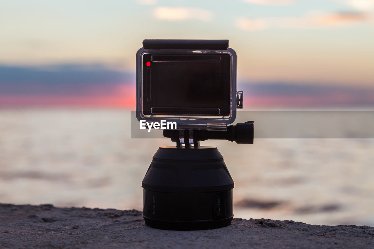 CLOSE-UP OF CAMERA ON BEACH AGAINST SKY