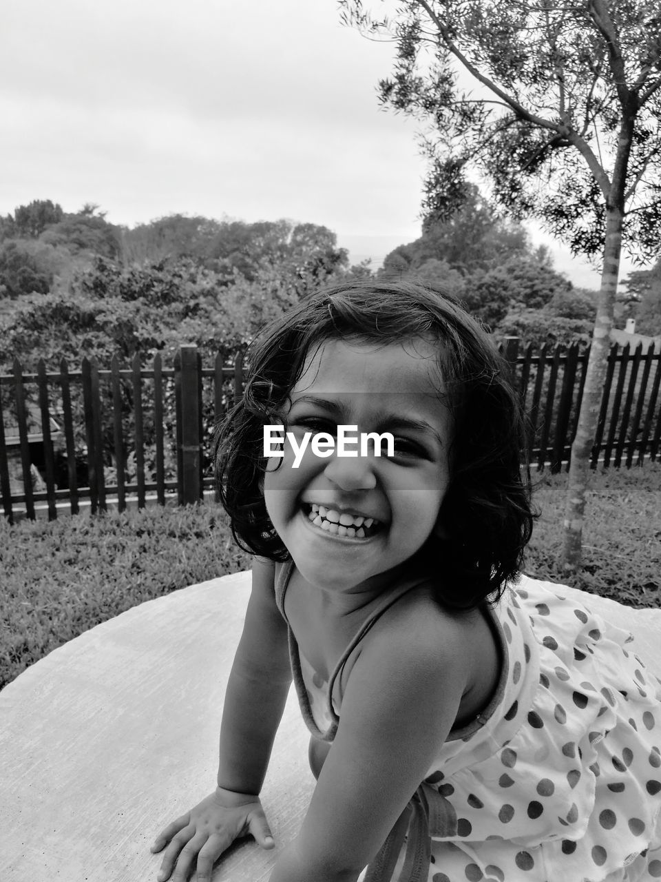 Portrait of happy girl playing in park against sky