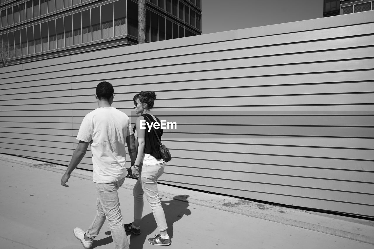 REAR VIEW OF PEOPLE WALKING ON FOOTPATH