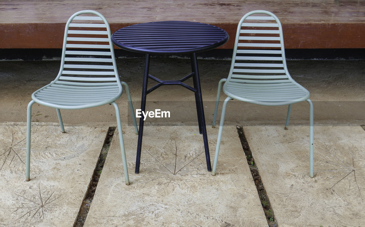 HIGH ANGLE VIEW OF EMPTY CHAIRS AGAINST SAND