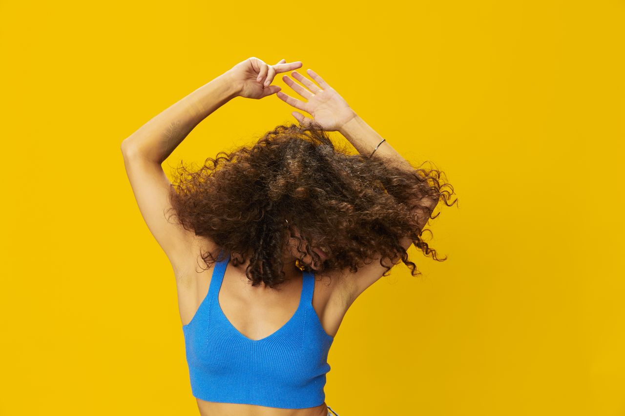 rear view of young woman with hand against yellow background