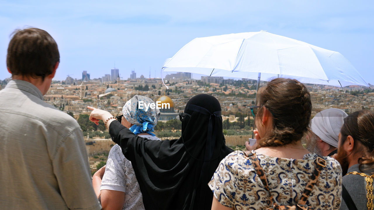 Rear view of people looking at cityscape during sunny day