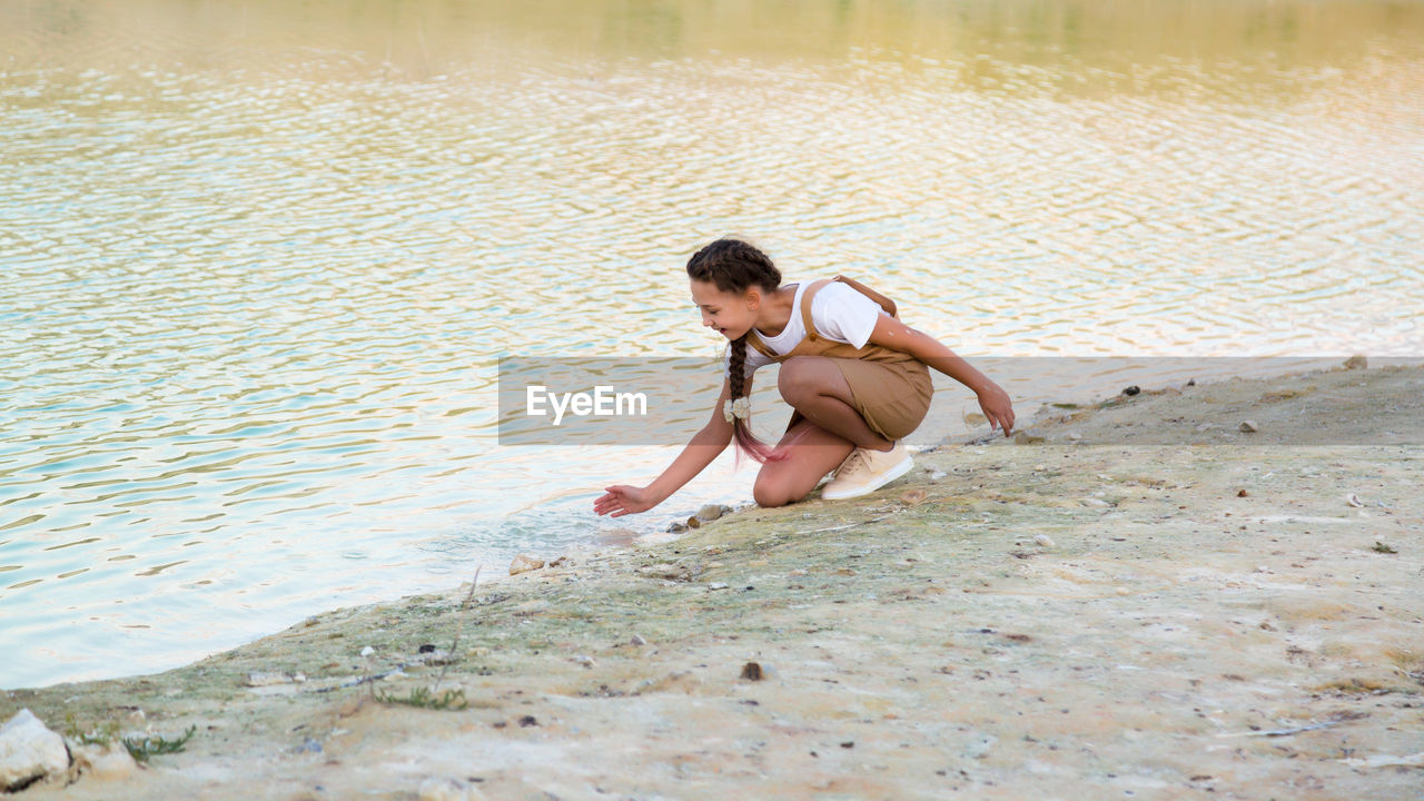 Teenage girl splashes water from the river and laughs.