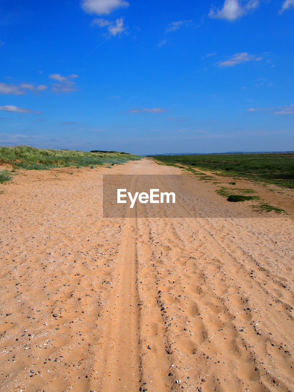 DIRT ROAD AMIDST FIELD AGAINST SKY